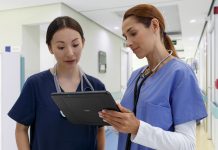 Two female nurses looking / reading a report on a tablet