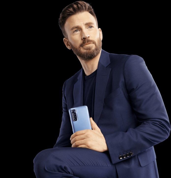 A mansitting on a chair poses for a picture holding Tecno Camon 17 Pro