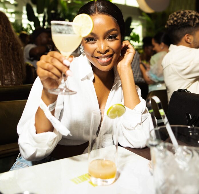South African TV personality K Naomi holding a Patrón Margarita cocktail glass