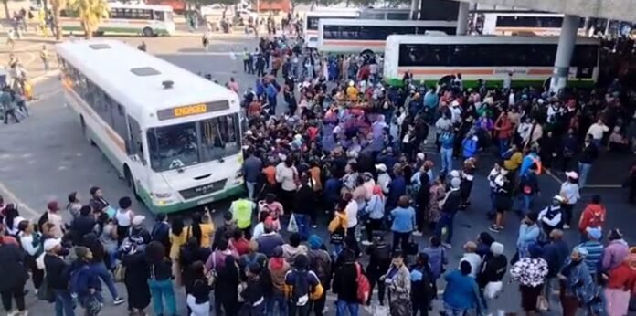 Commuters gather around a bus at a terminal during a previous taxi strike