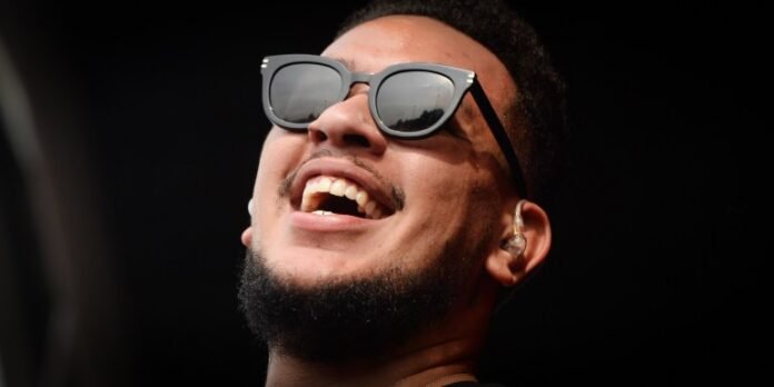 Smiling AKA wearing sunglasses, captured during a live performance.