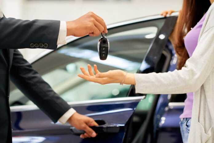 Car sales man giving a customer her new car keys.