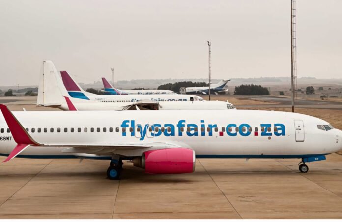 A FlySafair airplane parked on the tarmac with other FlySafair aircraft in the background.