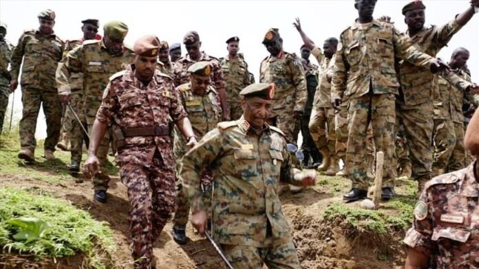 Sudanese military leaders in camouflage uniforms walk downhill near Port Sudan amid political tensions.