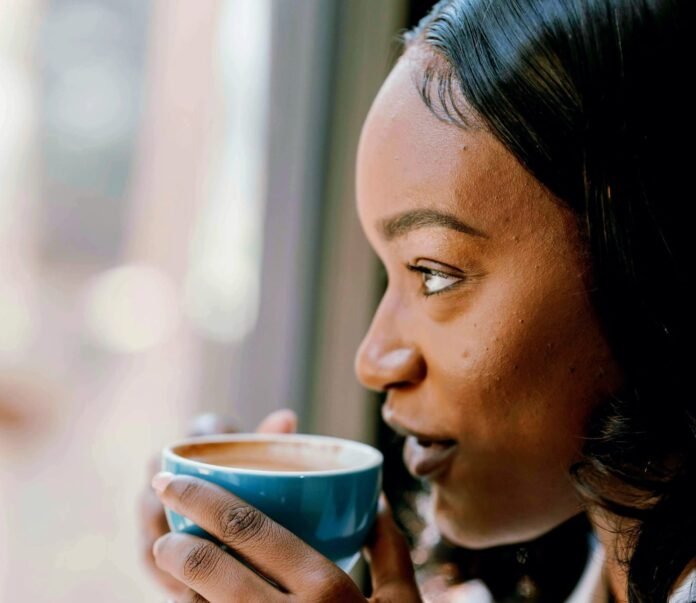 Woman sipping coffee by a window.