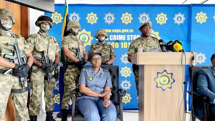 KZan Police Commissioner Nhlanhla Mkhwanazi addresses media, flanked by armed officers.