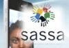 SASSA confirms rollout of new 2026 online self-service system Smartphone scanning a woman’s face for SASSA biometric verification, overlaid with the SASSA handprint logo.