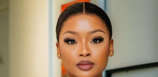 SIU responds to claims linking influencers to corruption probe A portrait of South African influencer and DJ Cyan Boujee, styled in a sleek black outfit with branded strap detailing across the neckline. She wears bold makeup with defined lashes and has her hair neatly tied back. The image is taken indoors with a softly blurred background.