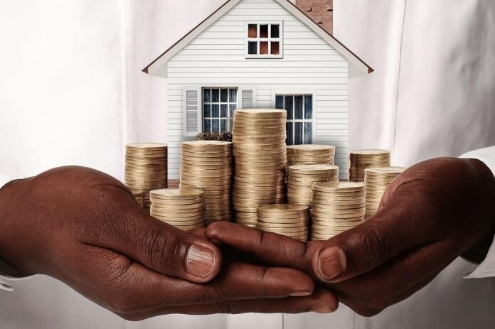 Hands holding gold coins and a house model.