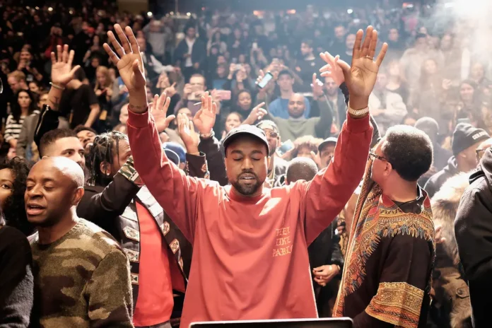 Kanye West raising his hands before a cheering crowd.