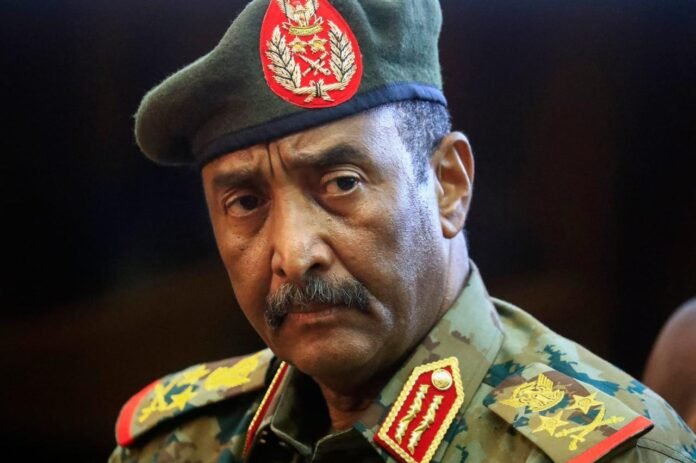 General Abdel Fattah al-Burhan in military uniform, gazing left in a dimly lit portrait