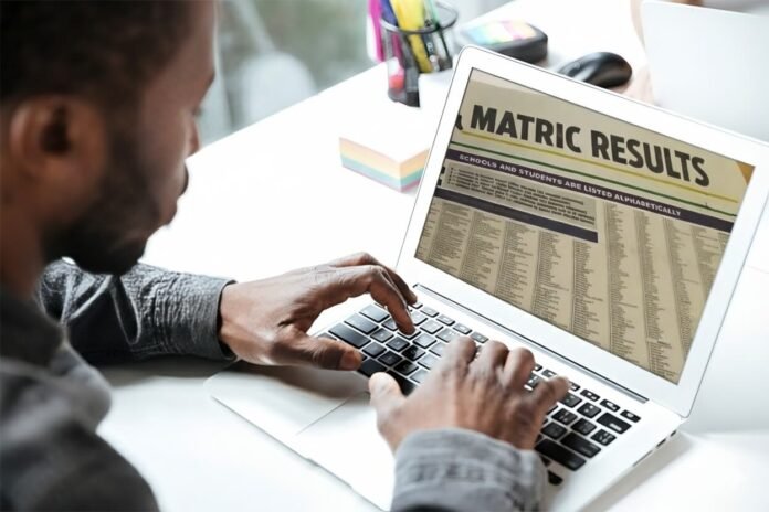 A young man looking at matric results on a laptop screen.