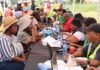 SASSA confirms February SRD payment dates — public comment opens on major rule changes SASSA staff assisting SRD grant beneficiaries at a community registration and verification centre, with residents seated across tables using laptops to check grant status and resolve payment issues.