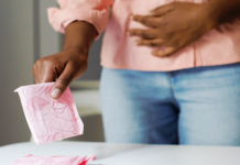 9 popular menstrual pads under investigation over toxic hormone disruptors Person holding a pink menstrual pad representing menstrual hygiene products under NCC investigation.
