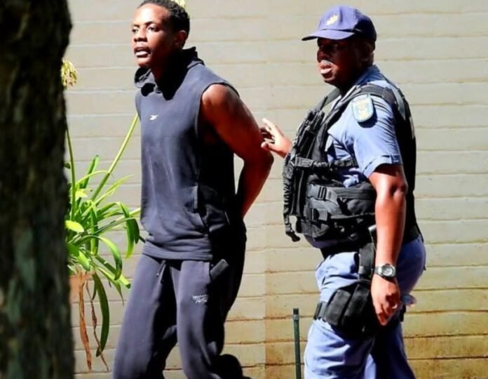 Bellarmine Chatunga Mugabe escorted by a South African police officer in Hyde Park Johannesburg during attempted murder investigation.