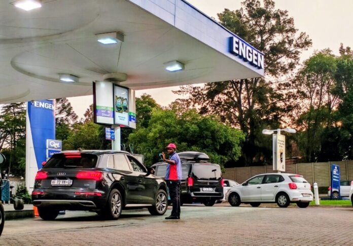 A fuel attendant assists motorists at an Engen petrol station on Witkoppen Road in Fourways, Johannesburg, at sunset.