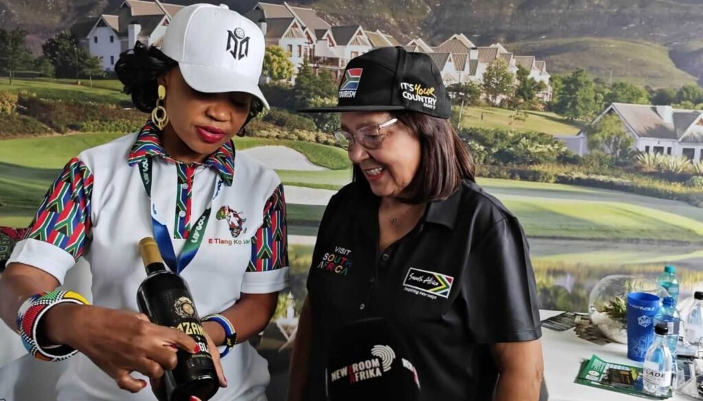Malethola Matube and Patricia de Lille stand with a bottle of wine at LIV Golf South Africa, highlighting local tourism and viticulture initiatives linked to the event.