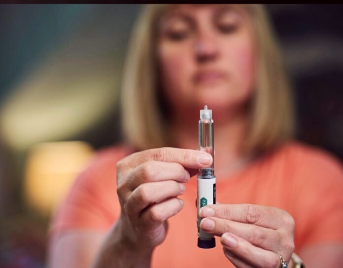 Close-up of a woman's hands holding a clear Ozempic-style injection pen for weight loss treatment.