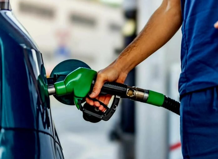 Close-up of a person refuelling a car at a petrol station as fuel prices fluctuate.