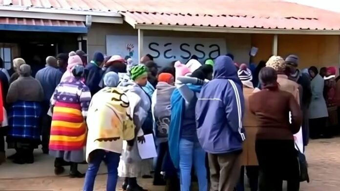 South African beneficiaries queue outside a SASSA office to collect social grant payments.