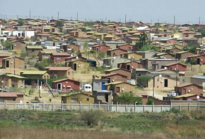 Aerial view of a South African RDP project with small, colourful houses and solar panels under a clear sky.