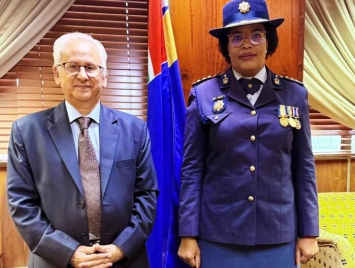 Firoz Cachalia and Acting SAPS National Commissioner Puleng Dimpane stand side by side in formal attire in front of a South African flag.