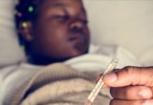 Health advisory issued as Gauteng malaria outbreak claims 11 lives Person holding thermometer with sick child lying in bed in background showing fever symptoms.