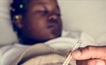 Health advisory issued as Gauteng malaria outbreak claims 11 lives Person holding thermometer with sick child lying in bed in background showing fever symptoms.