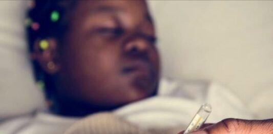 Health advisory issued as Gauteng malaria outbreak claims 11 lives Person holding thermometer with sick child lying in bed in background showing fever symptoms.