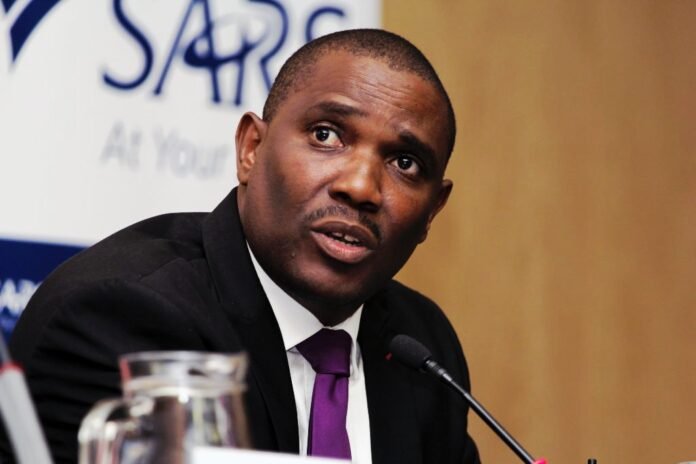 ​Portrait of Dr Johnstone Makhubu next to a laptop with the SARS eFiling portal and the South African Reserve Bank logo.