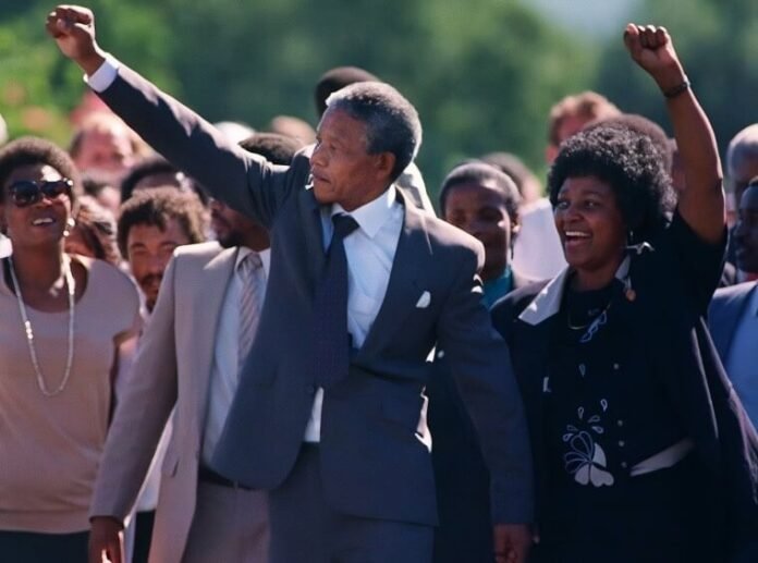 Nelson Mandela and Winnie Madikizela-Mandela walking hand in hand after his 1990 release from Victor Verster Prison, both raising clenched fists in the Amandla salute.