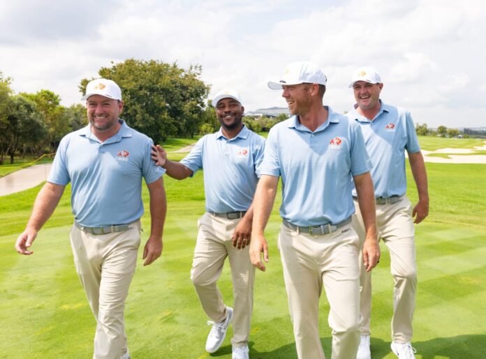 OKGC golfers Graeme McDowell, Harold Varner III, Talor Gooch and Jason Kokrak walk together laughing on a green fairway in matching uniforms.