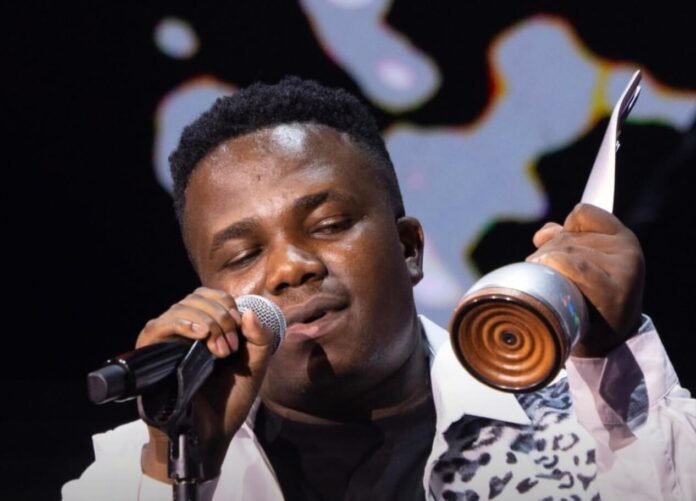 Umafikizolo (Khethukuthula Mhlongo) singing into a microphone and holding a silver trophy on stage at the Metro FM Awards 2026.
