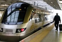 Gautrain’s Gau Express e-hailing service: Everything you need to know A gold-and-silver Bombardier Gautrain train at a station platform with a commuter walking alongside pulling a black suitcase.