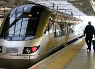 Gautrain’s Gau Express e-hailing service: Everything you need to know A gold-and-silver Bombardier Gautrain train at a station platform with a commuter walking alongside pulling a black suitcase.