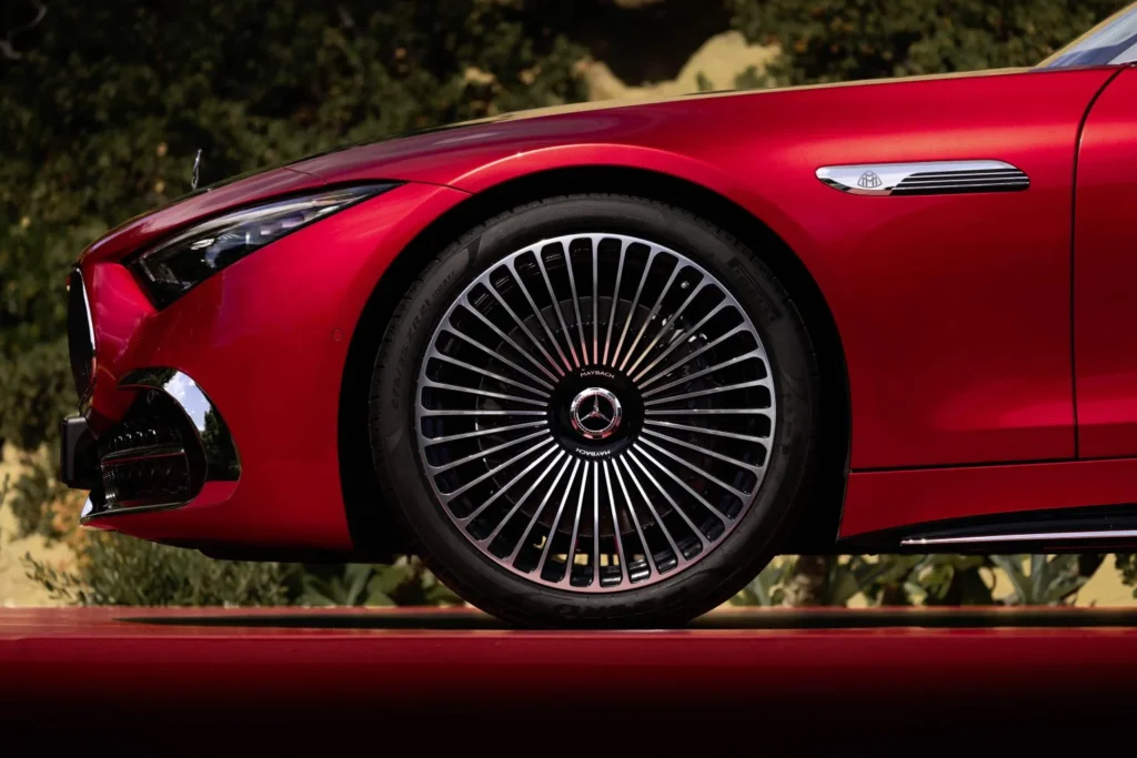 Side profile detail of the red Mercedes-Maybach SL 680 showcasing the exclusive multi-spoke twenty-one-inch alloy wheels and chrome wing badging.