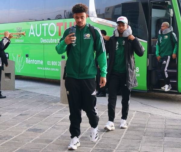 Bafana Bafana players stepping off bus in Mexico wearing team tracksuits ahead of 2026 World Cup match.