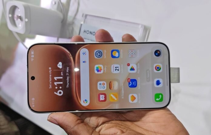 Hand holding HONOR 600 smartphone displaying home screen at Gallagher Convention Centre Midrand launch