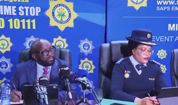 SAPS officials hold media briefing on crime prevention and operational readiness with Crime Stop 10111 backdrop.