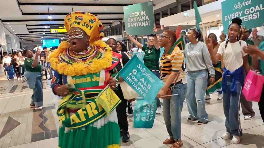 Mama Joy leads supporters during Banyana Banyana's WAFCON send-off at OR Tambo Airport.