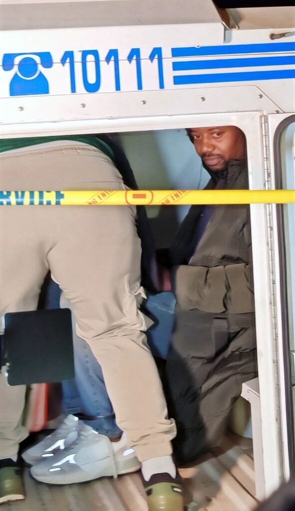 SAPS officers escort Ndodana "Mark" Tshuma into a police vehicle following his arrest in Kensington, Johannesburg.