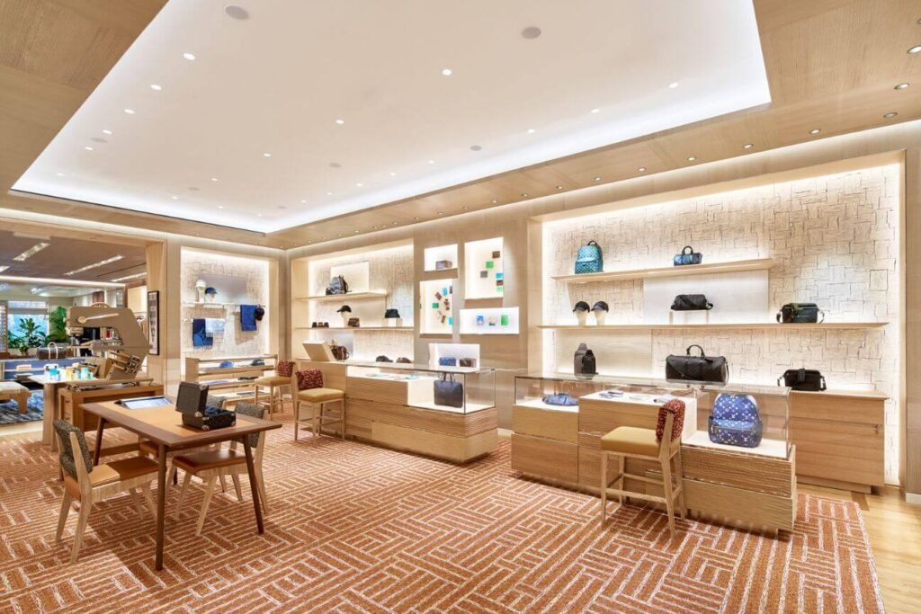 Men's collection at Louis Vuitton's V&A Waterfront flagship, leather bags on stone-textured shelving.