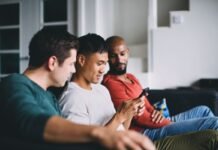 Digital lifestyle shifts: How technology, sports, and Virgin Bet are transforming South African entertainment Three men sitting on a couch in a living room and looking at a smartphone together.