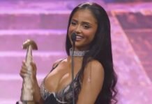 SAMA 2026: How Tyla gave anticlimactic awards night its big moment Tyla smiles at a microphone while holding her SAMA32 trophy on stage.