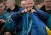 As Russia-Ukraine war escalates, UAE keeps diplomatic channels Open Released Ukrainian service members sit together, wrapped in Ukrainian flags, as one man forms a heart with his hands.