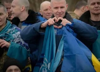 As Russia-Ukraine war escalates, UAE keeps diplomatic channels Open Released Ukrainian service members sit together, wrapped in Ukrainian flags, as one man forms a heart with his hands.