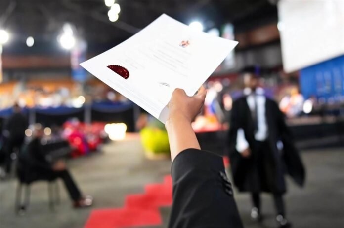 Graduate holds up university certificate with red seal at ceremony