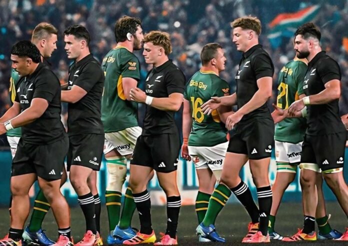 Springboks and All Blacks players exchange handshakes on a floodlit pitch after their match