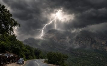 Heritage Day long weekend weather: What to expect across South Africa Mountain highway curves through a green valley as lightning strikes beneath dark thunderclouds and rain haze