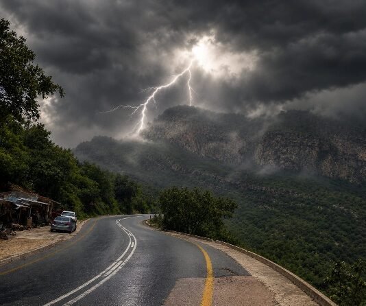 Heritage Day long weekend weather: What to expect across South Africa Mountain highway curves through a green valley as lightning strikes beneath dark thunderclouds and rain haze